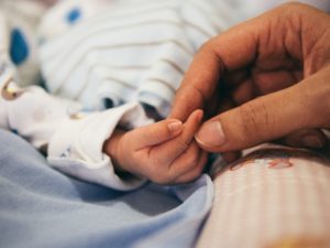 Image of a newborn baby's hand being gently held by a parent