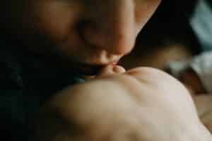 A mother kissing a newborn's nose - taken from the side